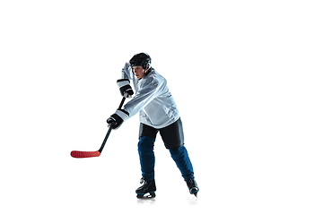 Image showing Young male hockey player with the stick on ice court and white background