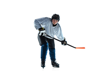 Image showing Young male hockey player with the stick on ice court and white background