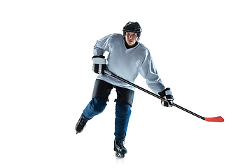 Image showing Young male hockey player with the stick on ice court and white background