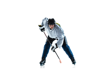 Image showing Young male hockey player with the stick on ice court and white background