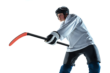 Image showing Young male hockey player with the stick on ice court and white background