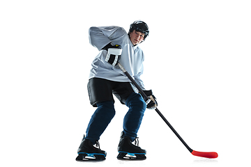 Image showing Young male hockey player with the stick on ice court and white background