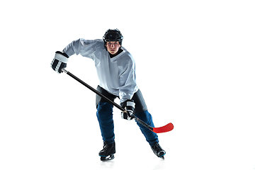 Image showing Young male hockey player with the stick on ice court and white background