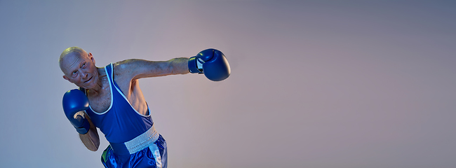 Image showing Senior man wearing sportwear boxing isolated on gradient studio background in neon light. Concept of sport, activity, movement, wellbeing. Copyspace, ad.