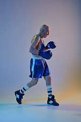 Image showing Senior man wearing sportwear boxing isolated on gradient studio background in neon light. Concept of sport, activity, movement, wellbeing. Copyspace, ad.