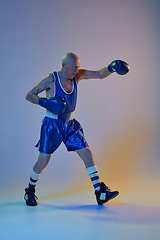 Image showing Senior man wearing sportwear boxing isolated on gradient studio background in neon light. Concept of sport, activity, movement, wellbeing. Copyspace, ad.
