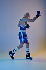 Image showing Senior man wearing sportwear boxing isolated on gradient studio background in neon light. Concept of sport, activity, movement, wellbeing. Copyspace, ad.