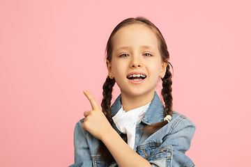 Image showing Happy kid, girl isolated on pink studio background. Looks happy, cheerful, sincere. Copyspace. Childhood, education, emotions concept