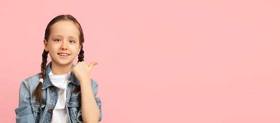 Image showing Happy kid, girl isolated on pink studio background. Looks happy, cheerful, sincere. Copyspace. Childhood, education, emotions concept
