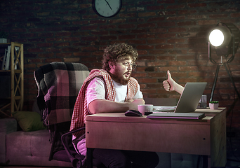 Image showing Young Caucasian man talking with friend online through laptop.