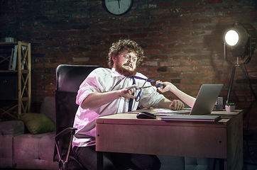 Image showing Young Caucasian man working at home online through laptop. Virtual reality.