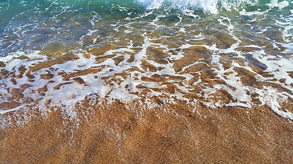 Image showing Clear sea water with white foam in the coastal sand