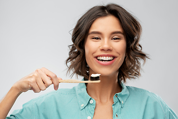 Image showing smiling woman with toothpaste on wooden toothbrush