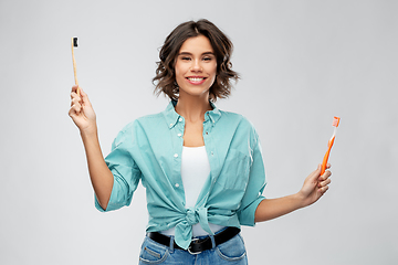 Image showing woman comparing wooden and plastic toothbrush