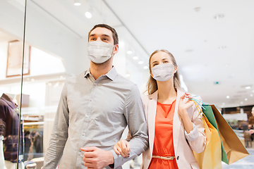 Image showing couple in medical masks with shopping bags in mall