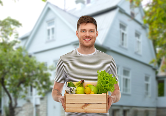 Image showing smiling man with food in wooden box over house
