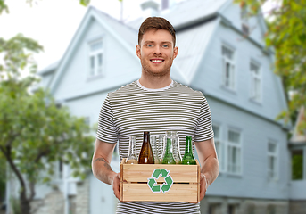 Image showing smiling young man sorting glass waste over house