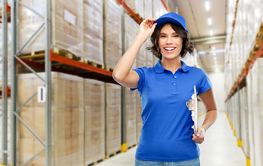 Image showing happy delivery girl with clipboard at warehouse