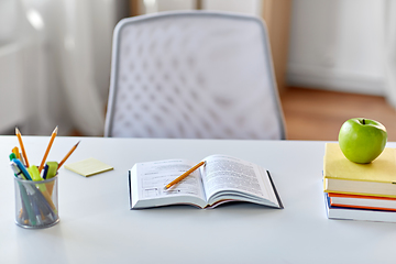 Image showing books, apple and school supplies on table at home