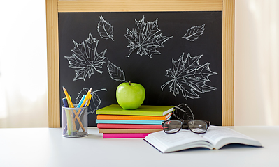 Image showing books, apple and school supplies on table at home