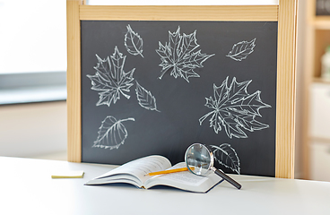 Image showing book with magnifier on table and chalkboard