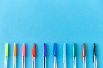 Image showing row of multicolored pens on blue background