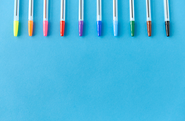 Image showing row of multicolored pens on blue background