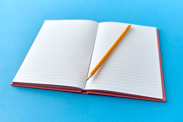 Image showing open notebook with pencil on blue background