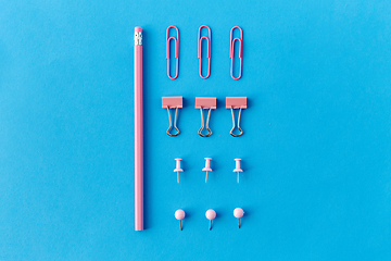 Image showing pink pencil, pins and clips on blue background