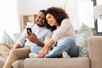 Image showing happy couple with smartphone and earphones at home