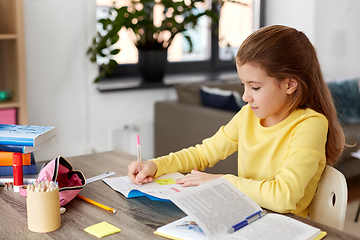 Image showing student girl with book writing to notebook at home