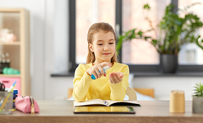 Image showing little student girl with hand sanitizer at home