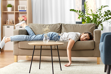 Image showing bored or lazy young woman lying on sofa at home