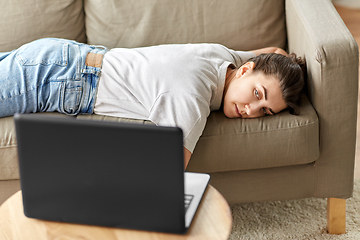 Image showing bored woman with laptop lying on sofa at home