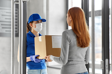 Image showing delivery girl in face mask giving parcel to woman