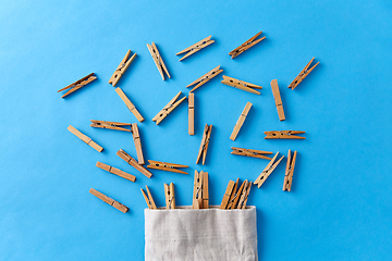 Image showing wooden clothespins in bag on blue background