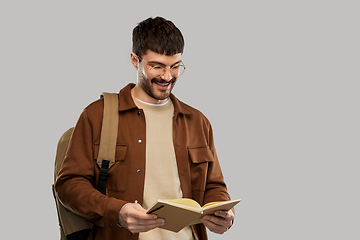 Image showing smiling young man with backpack reading diary