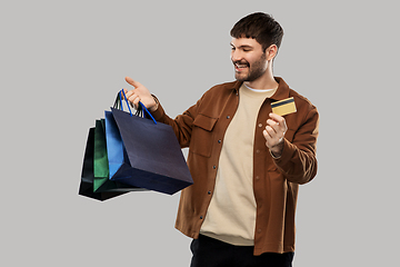 Image showing happy young man with shopping bags and credit card