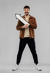 Image showing smiling young man holding big white arrow