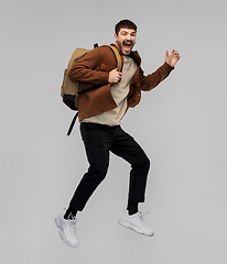 Image showing smiling young man with backpack jumping in air