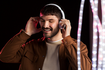 Image showing man in headphones over neon lights of night club