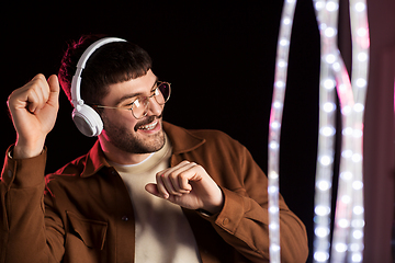 Image showing man in headphones over neon lights of night club