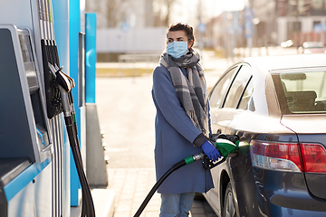 Image showing woman in mask filling her car at gas station