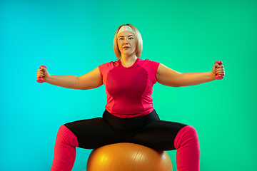 Image showing Young caucasian plus size female model\'s training on gradient green background