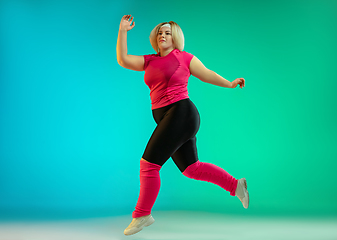 Image showing Young caucasian plus size female model\'s training on gradient green background