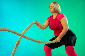 Image showing Young caucasian plus size female model\'s training on gradient green background