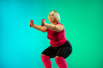 Image showing Young caucasian plus size female model\'s training on gradient green background