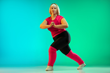 Image showing Young caucasian plus size female model\'s training on gradient green background