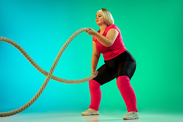 Image showing Young caucasian plus size female model\'s training on gradient green background