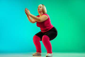 Image showing Young caucasian plus size female model\'s training on gradient green background